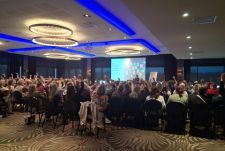 Leraar zit op tafel met een schrijfblok in de hand om de klas te observeren