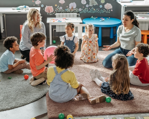 Jonge Kind-Leerkracht praat met kinderen in de kring