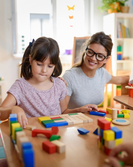 Kind speelt samen met leraar met blokken aan tafel