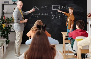 Leraar en leerling bij schoolbord Leraar en leerling staan bij het schoolbord voor een wiskunde opdracht.