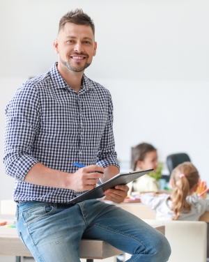 Leraar zit op tafel met een schrijfblok in de hand om de klas te observeren