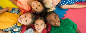 Onderwijs-aan-nieuwkomers-nt2-leerlingen-in-company_tegel Kinderen van diverse komaf liggen lachend op de grond